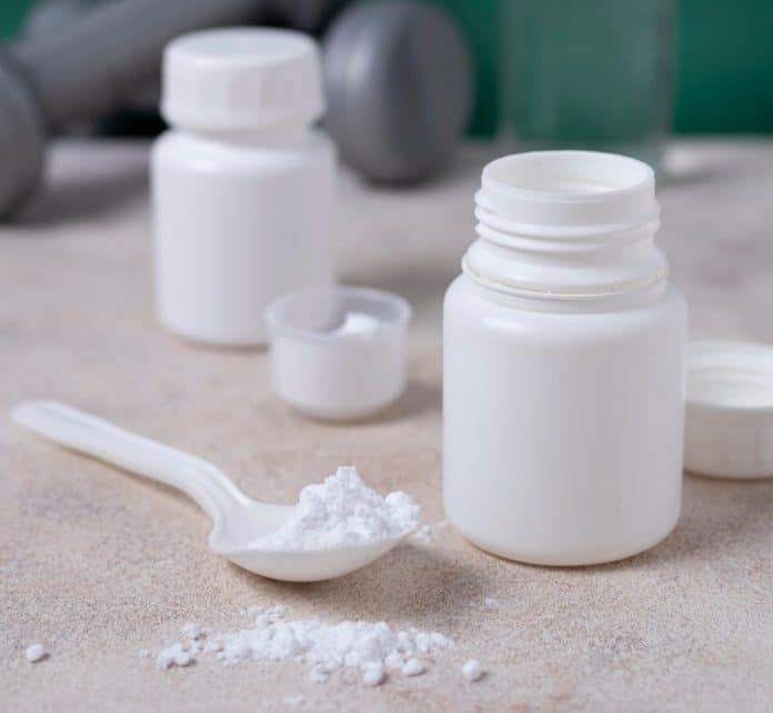 créatine Des pots de créatine avec une cuillère et de la poudre.