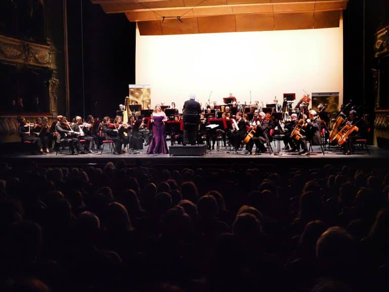 Une scène et des artistes qui jouents devant un large public dans le noir.