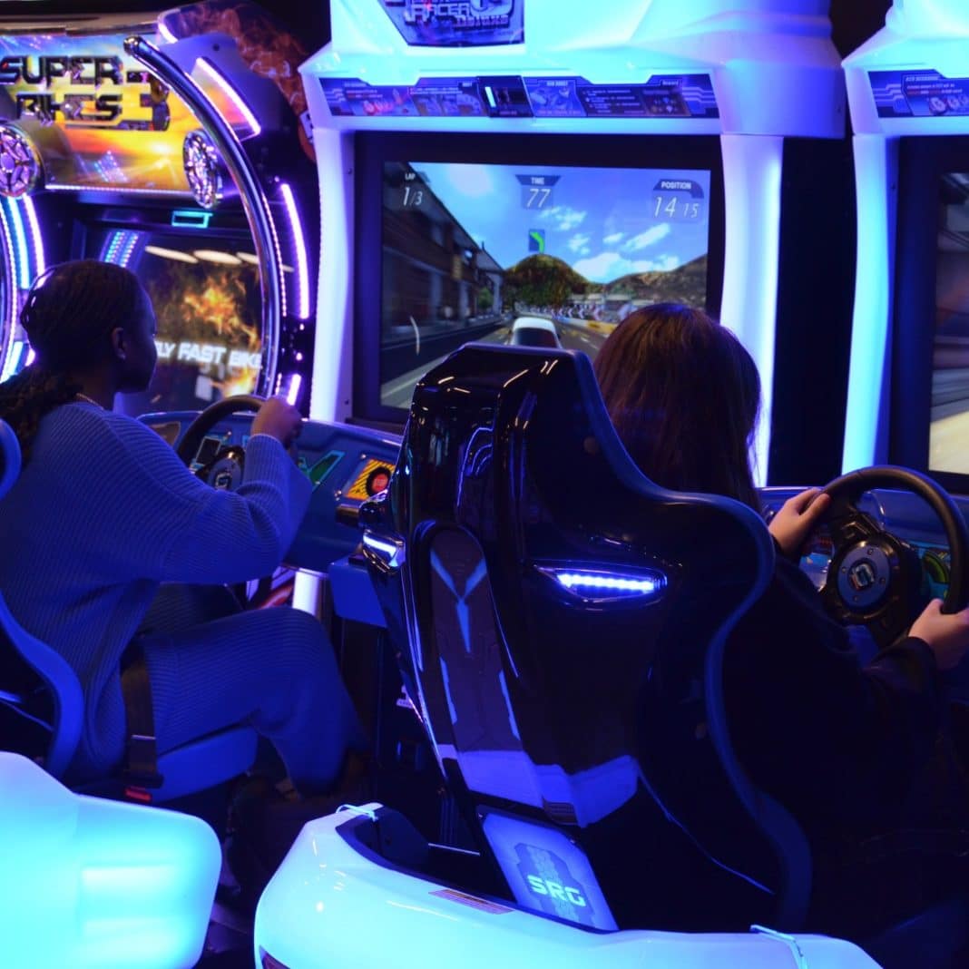 Des jeunes joue dans des simulateurs automobile.