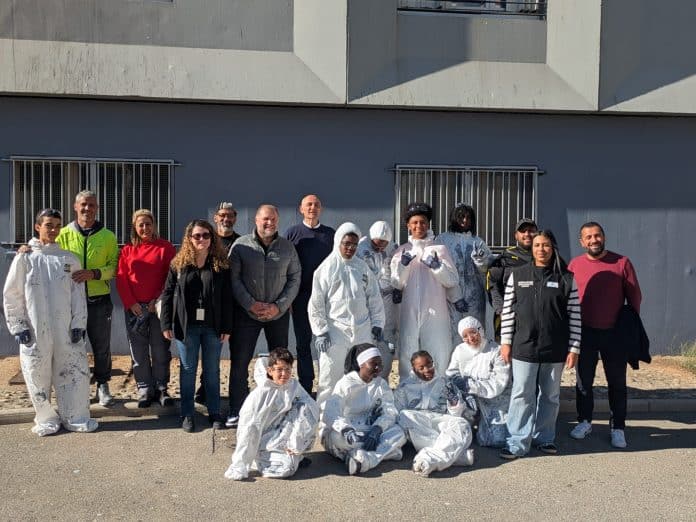 les jeunes du quartier de Bon Voyage participant au chantier solidaire, en combinaison, posant avec l'équipe de l'association paje et les représentant de Côte d'Azur Hbaitat, devant le bâtiment fraichement repeint