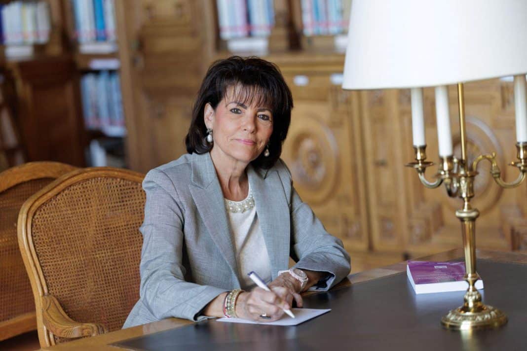 La Sénatrice Dominique Estrosi Sassone à bon bureau avec un stylo à la main regardant la caméra.