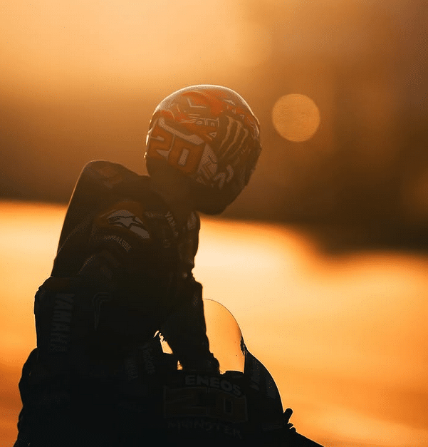Le pilote Niçois se retourne sur sa Yamaha alors que le soleil se couche sur la piste donnant une lumière orange.
