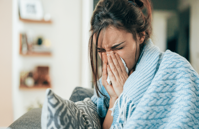 Grippenet _ Covidnet 3 Une femme dans un plaid se mouche.