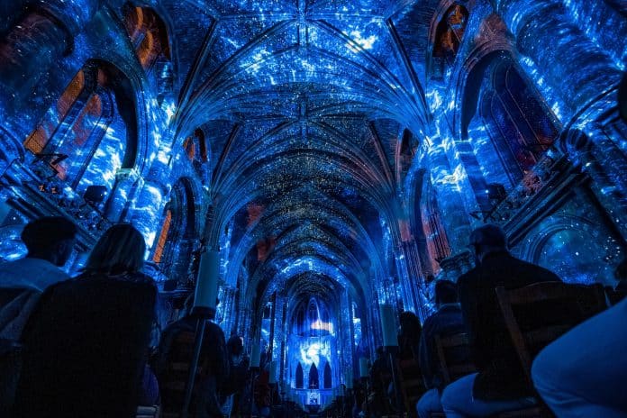 Le plafond de la basilique éclairé en bleu avec des ombres et les spectateurs installés sur les bancs.