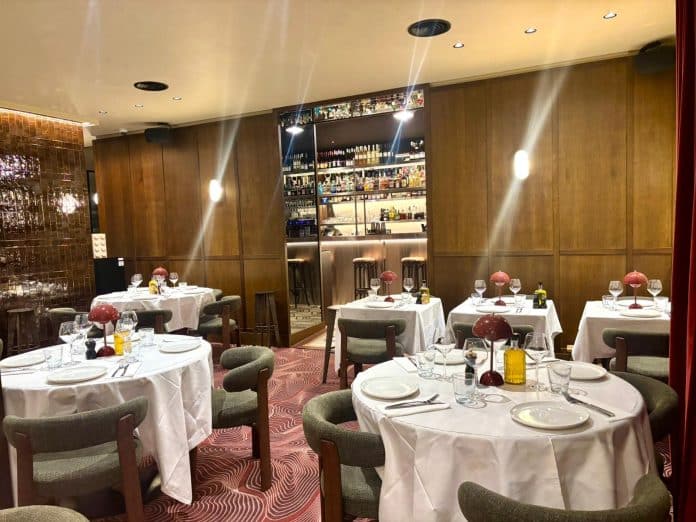 Les tables rondes du restaurant l'Uzine dans la salle de réception dans une ambiance boisée et ancienne.