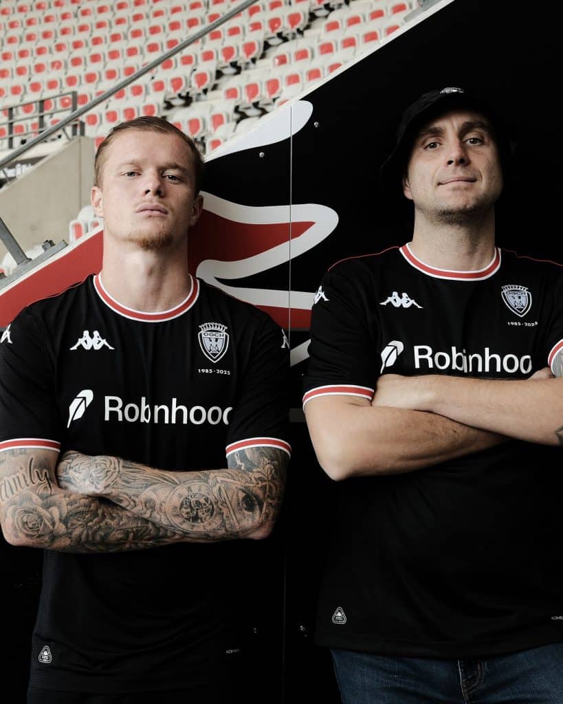 Deux supporters de l'OGC Nice avec le maillot noir dans le stade les bras croisés.