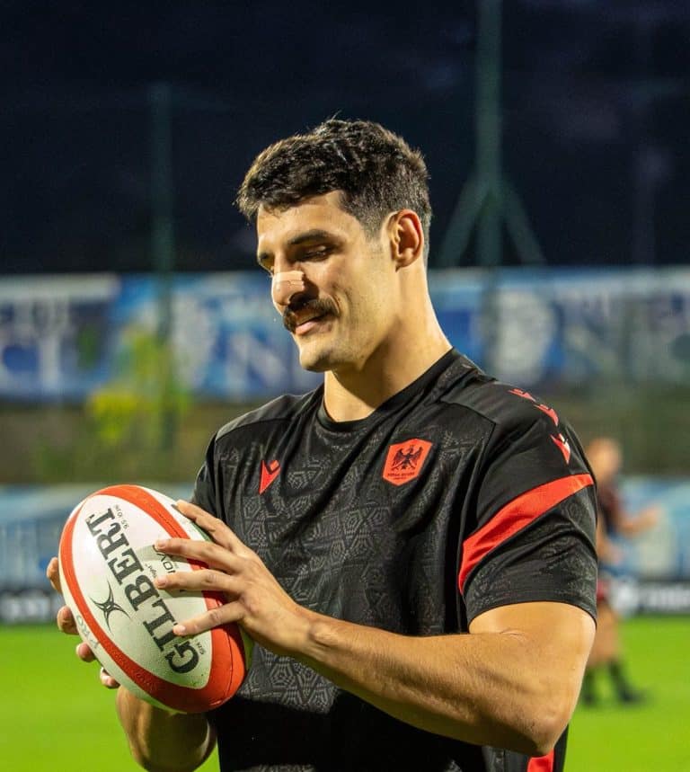 Un joueur de Nissa Rugby avec le sourire, ballon en main en tenue noir.