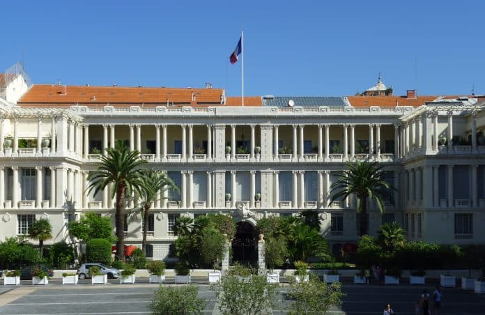 Le palais des Rois Sardes de Nice entouré de palmiers en plein coeur du centre ville dans une architecture ancienne blanche.
