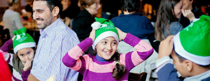 Des enfants avec des bonnets de pères noël vert.