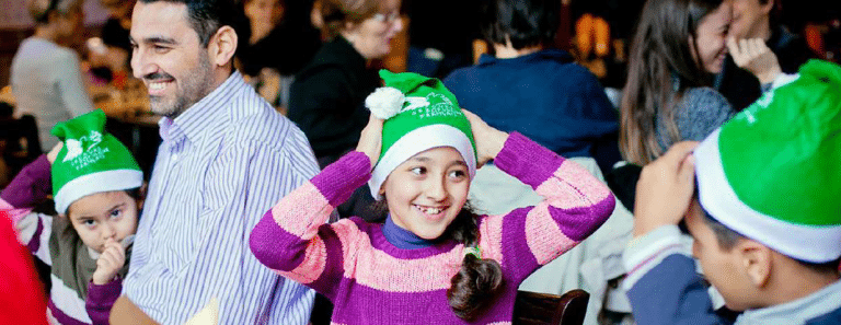 Des enfants avec des bonnets de pères noël vert.