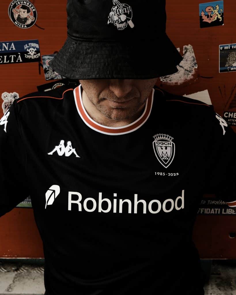 Un supporter avec un bob de supporter au couleurs de la populaire sud en noir et le maillot de la même couleur.