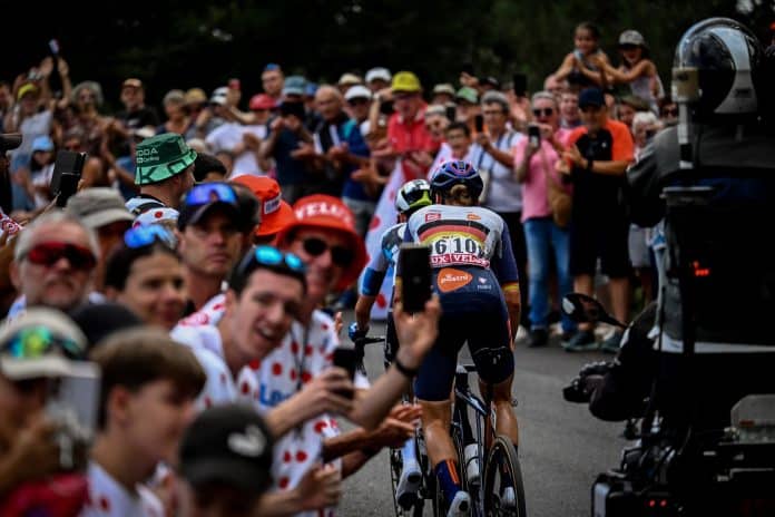 La foule regarde le passage des femmes du Tour de France au bord de la route en tapant dans les mains.