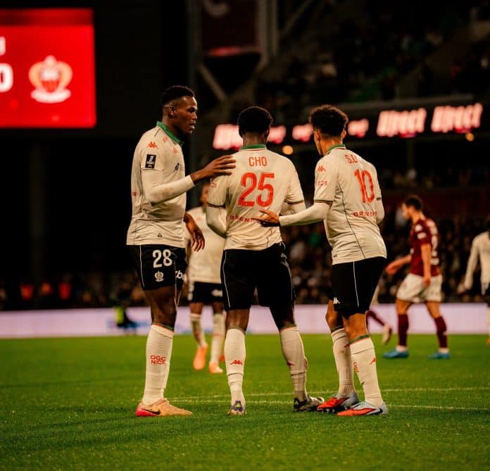 Des joueurs de l'OGC Nice s'encouragent sur la pelouse avec le maillot blanc, vert et rouge.