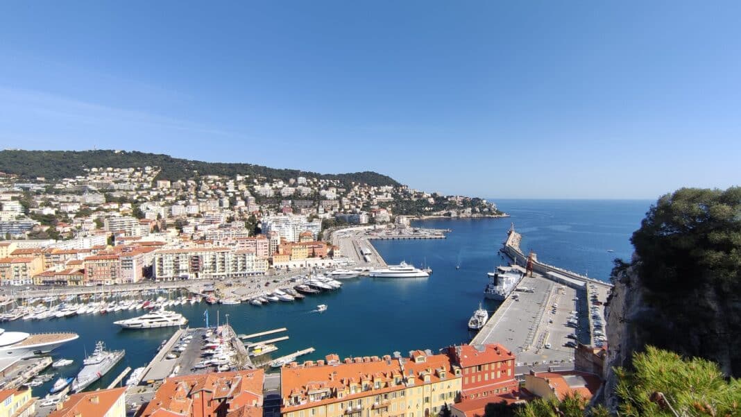 Le port de Nice vue de la colline du château en hauteur. avec des habitations, la mer et des bateaux de différentes tailles.