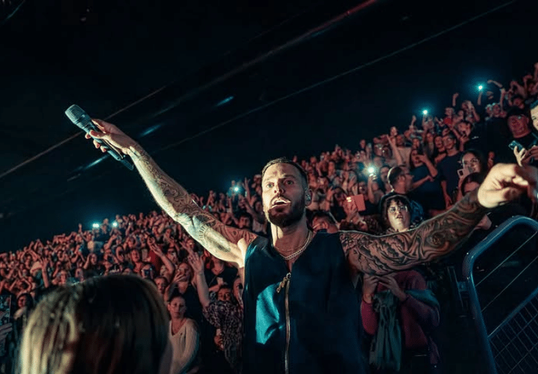 Le chanteur Matt Pokora dans la foule tend son micro pour faire participer le public présent.
