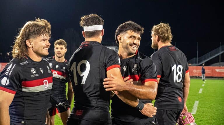 Les joueurs de Nissa Rugby heureux se congratulent sur le terrain dans leur tenue noir.