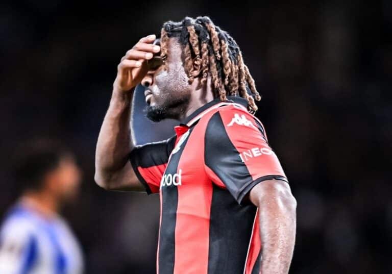 Le joueur de l'OGC Nice Terem Moffi avec le maillot du club rouge et noir se tient la tête en match.