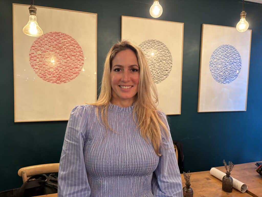 Céline Forjonnel, tête de liste de « Nice Démocratie Directe », sourit dans un restaurant après la conférence de presse. Elle porte un haut bleu.