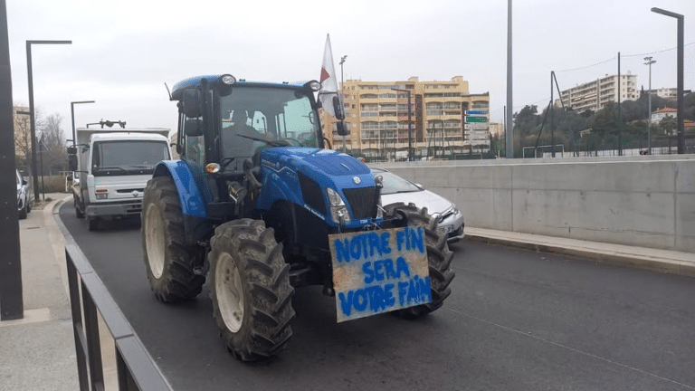 Un tracteur bleu au milieu de la circulation avec un panneau à l'avant disant : notre fin sera votre fain.
