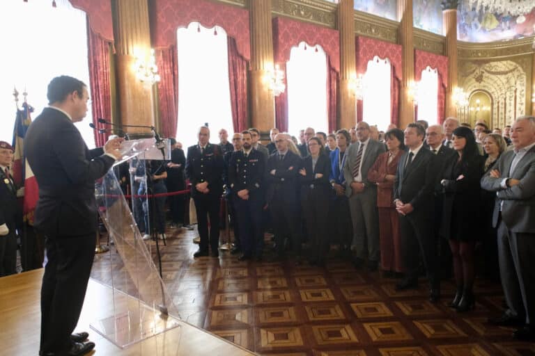 Le Préfet des Alpes-Maritimes devant une grande assemblée debout composée d'élus et de responsables des forces de l'ordre, pompiers....