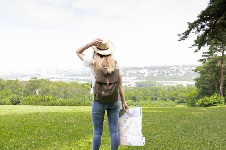 Femme tenant une carte dans l’herbe avec la mer en arrière-plan