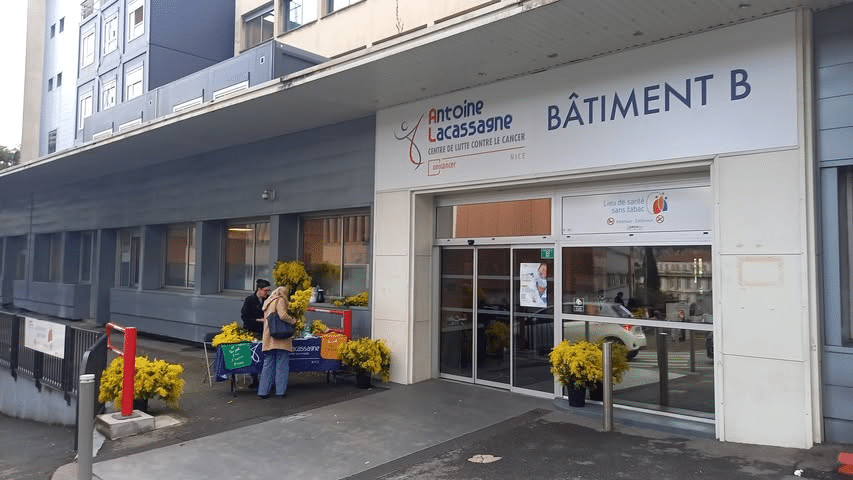 A woman taking a bouquet of mimosa at the mimosa stand in front of the hospital