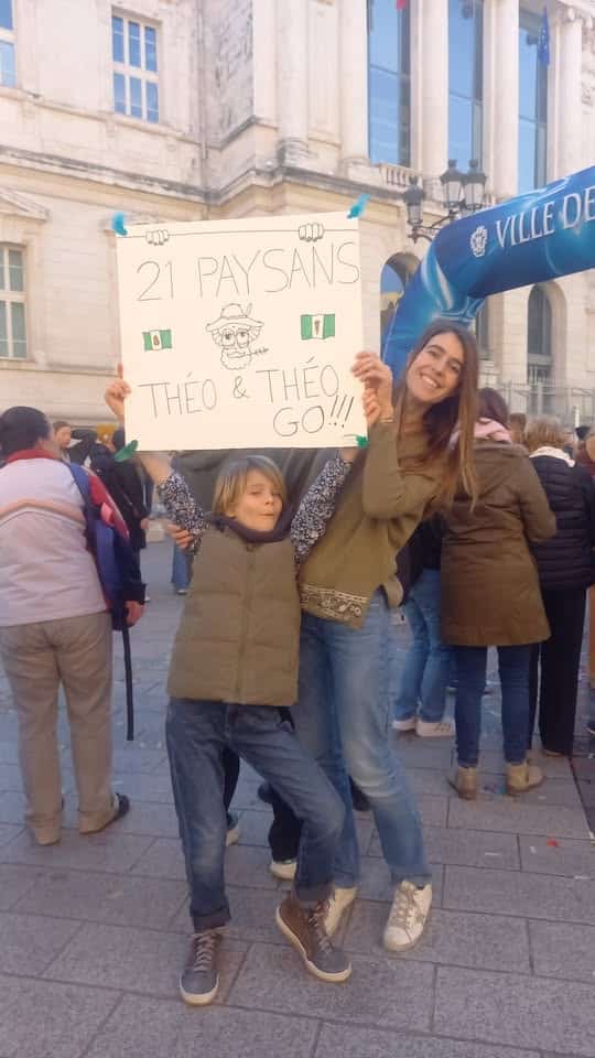 Une mère et son fils qui brandissent un panneau avec écrit "21 Paysans" dessus