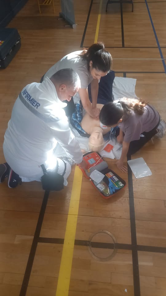 une mere sa fille et un infirmier font les premiers secours à un mannequin au sol