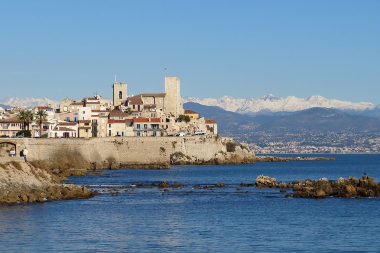 La villes d'Antibes dans les Alpes-Maritimes avec un vue sur le fort au bord de la mer et les montagnes enneigées.
