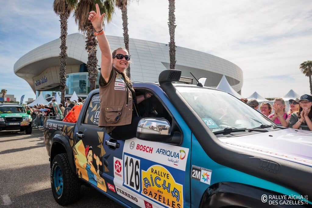 A rallye des gazelles participant sticking out of her car's window