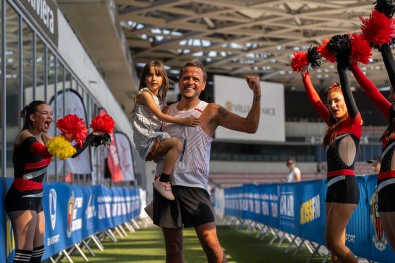 La Run by On Air avec un papa qui franchit la ligne d'arrivée de la course avec sa fille dans les bras.
