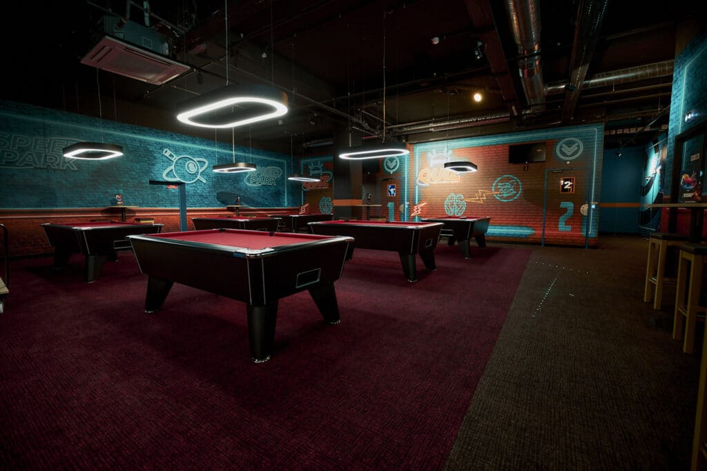 Un espace billard dans le speed park de Shopping Riviera dans une ambianc tamisée et des couleurs rouge sur les billards.