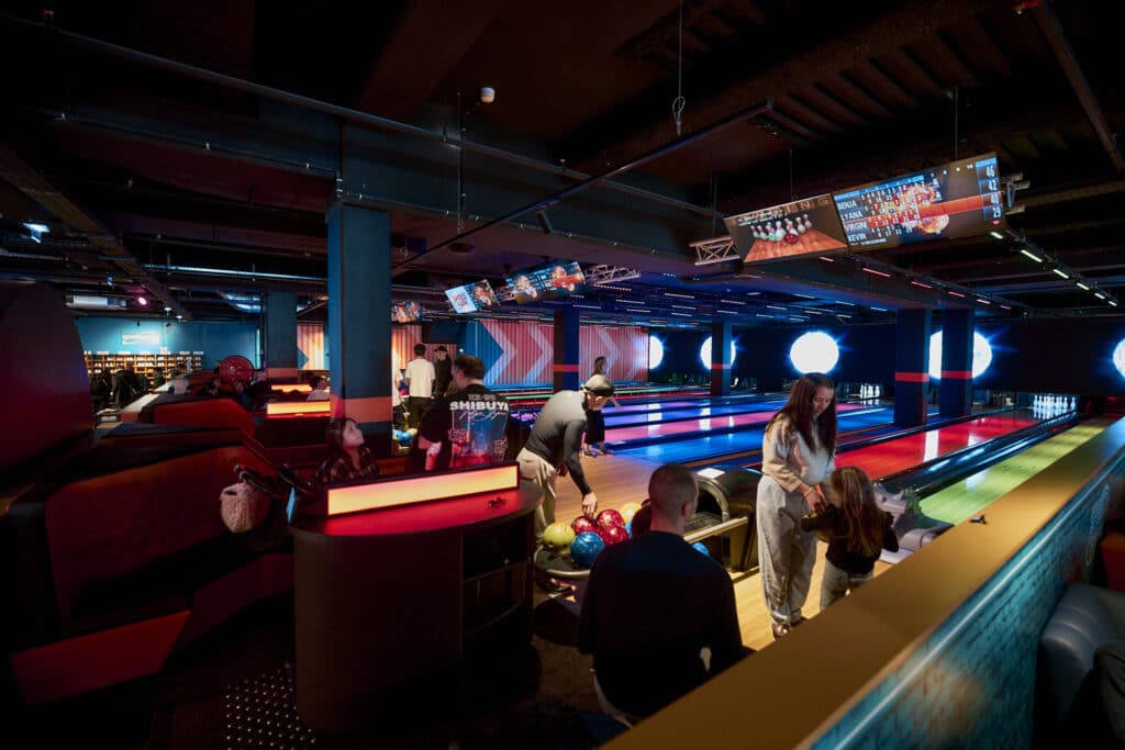 Des joueurs s'amusent au bowling sur les nouvelles pistes dans une ambiance américaine très éclairée.