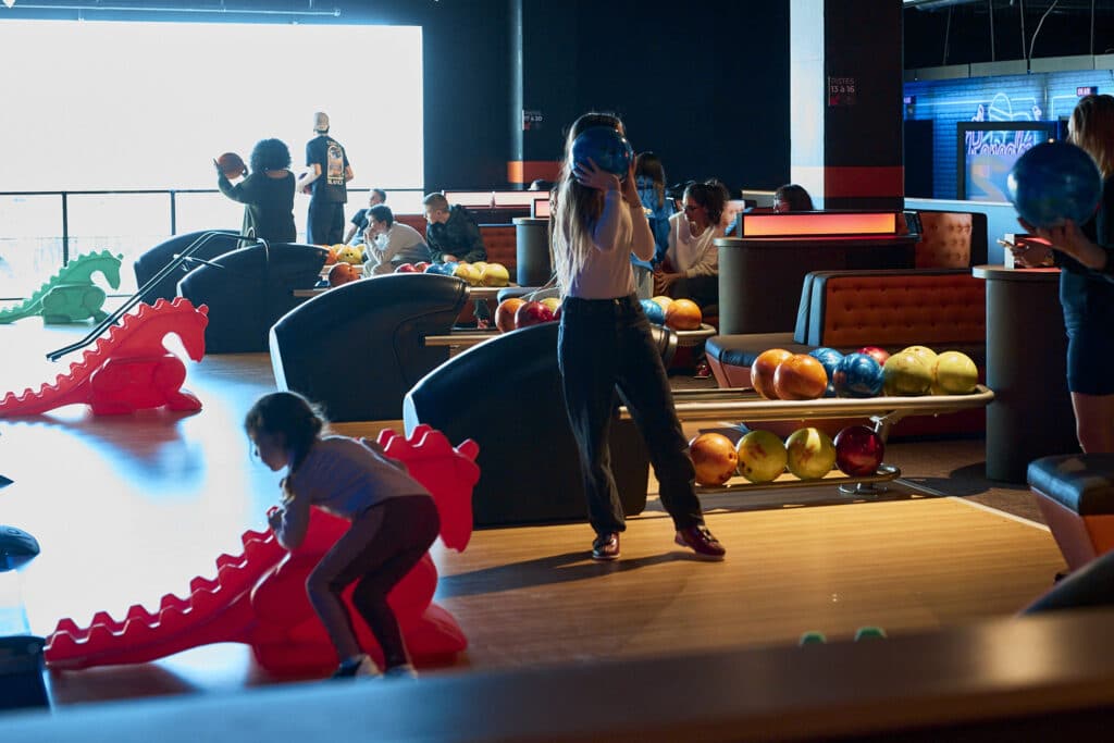 Des joueurs s'amusent au bowling sur les nouvelles pistes dans une ambiance américaine très éclairée.