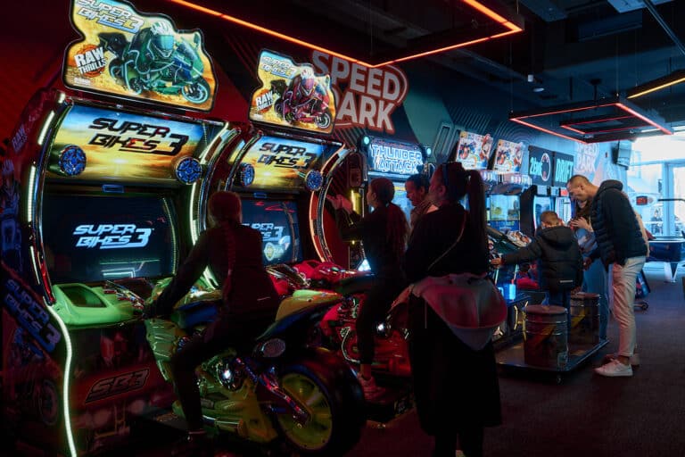 Des parents et enfants s'amusent sur des machines de jeux vidéo.