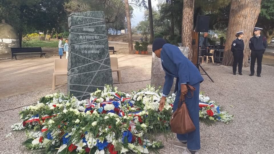 Un jeune Niçois dépose une rose blanche sur le tapis de fleurs au milieu des stèles, un geste de mémoire et de respect pour les victimes du terrorisme