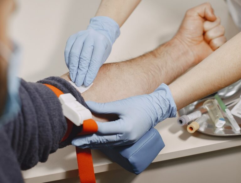 Une infirmière pose un garrot pour préparer une prise de sang sur un patient.