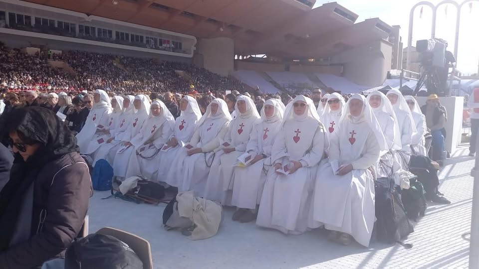 soeurs qui écoutent religieusement la messe du pape au stade