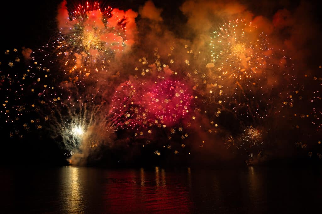 Le feu d'artifice du Carnaval de Nice tiré sur la mer devant la Promenade des Anglais. Une explosion de couleurs rouge, oragne et jaune.