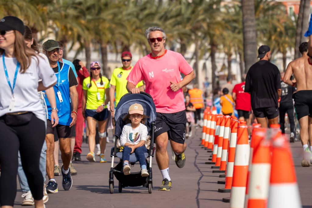 Un homme court en rose en poussant la poussette avec son enfant lors de la No Finish Line 2026.
