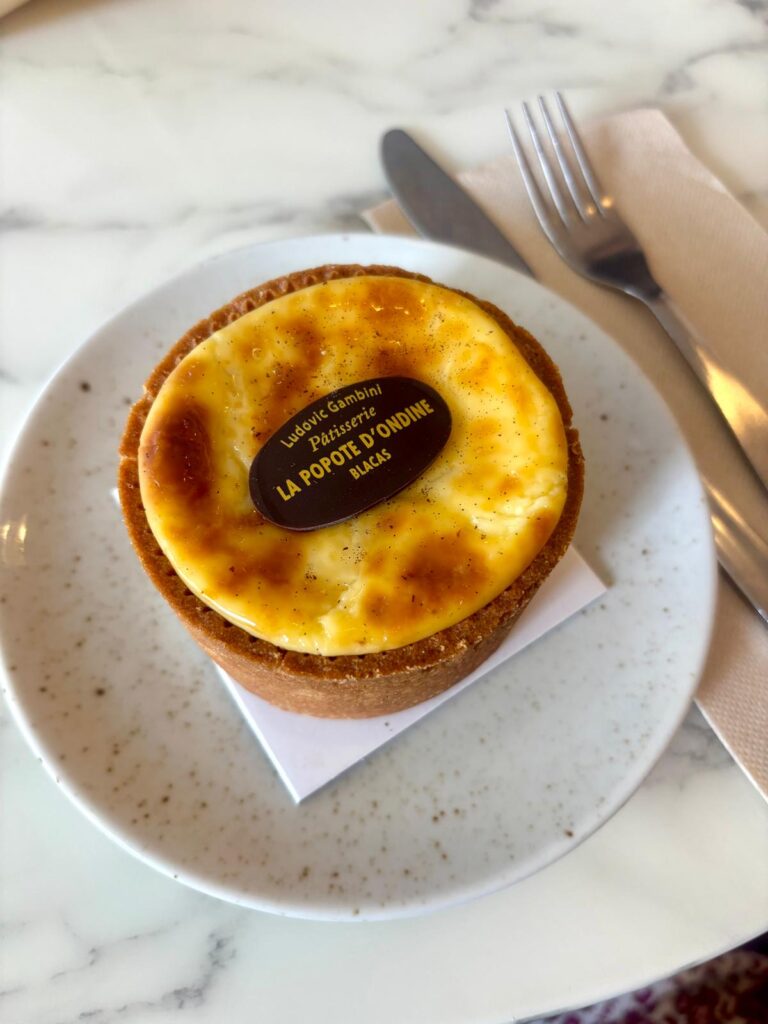 Un flan rond en tartelette avec le nom de la pâtisserie dessus.