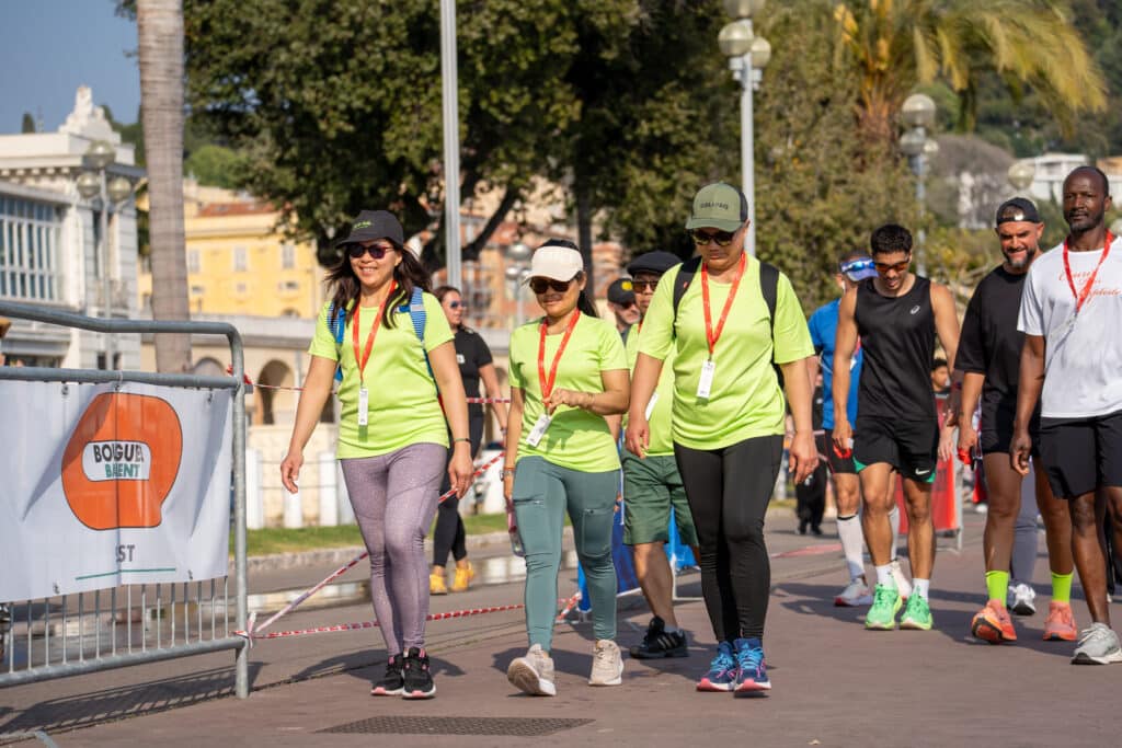 Des participants de la No Finish Line de Nice 2026 marchent en tee-shirt vert fluo.