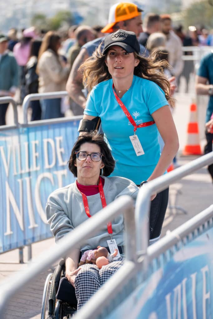 Une bénévole court en poussant une personne handicapée lors de la No Finish Line 2026 de Nice.