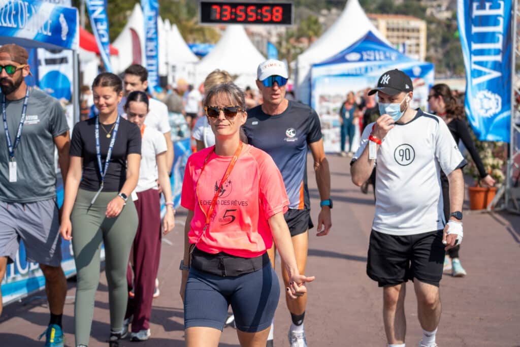 Des participants de la No Finish Line 2026 de Nice marchent sur la promenade des Anglais en profitant de la mer.