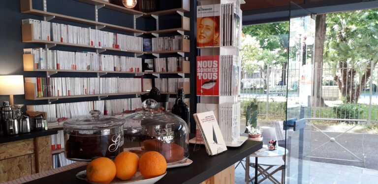 La librairie les Parleuses à Nice avec des romans dans des étagères, des gâteaux et des oranges sur un comptoir.