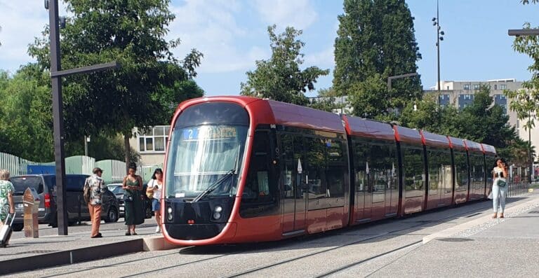 La ligne deux et trois du tramway de Nice de couleur rouge à une station pour déposer et récupérer des passagers.