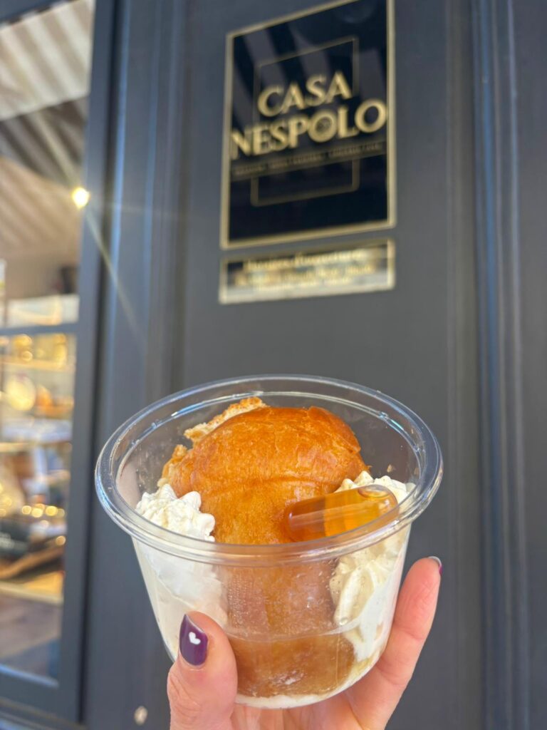 Le Baba au rhum de la Casa Nespolo dans un verre en plastique avec de la crème autour.