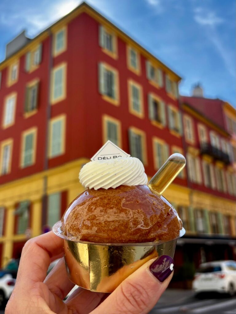 Le baba au rhum de la pâtisserie Deli Bo dans un pot doré avec une pipette de rhum et de la crème sur le dessus.