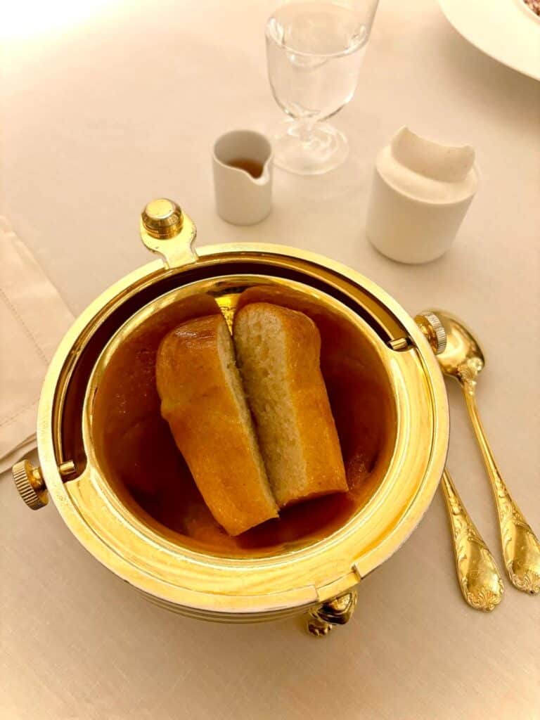 Le baba au rhum du restaurant le Louis XV de Monaco dans une assiette en or dans des couver en or. Le baba est ouvert en deux et beigne dans le rhum.