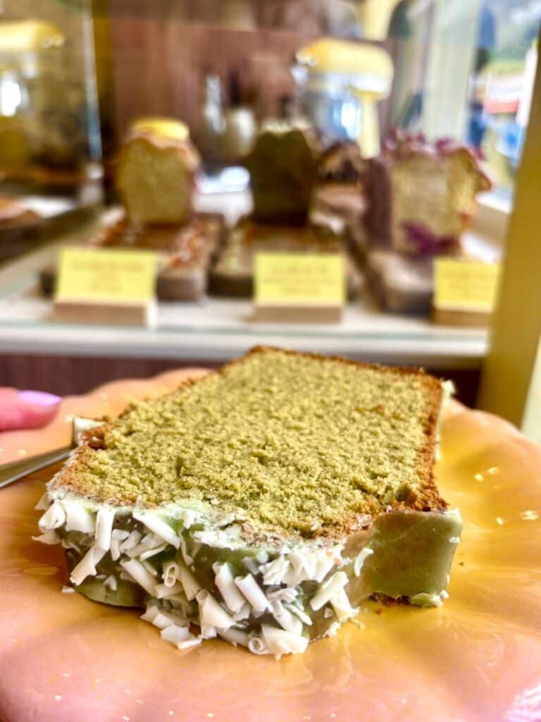 Une tranche de cake verte avec du toping blanc sur le dessus.